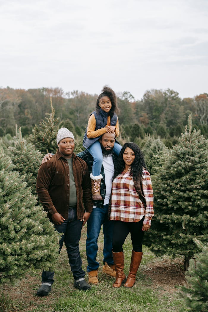 A joyful family stands together in a field of Christmas trees, celebrating togetherness.
